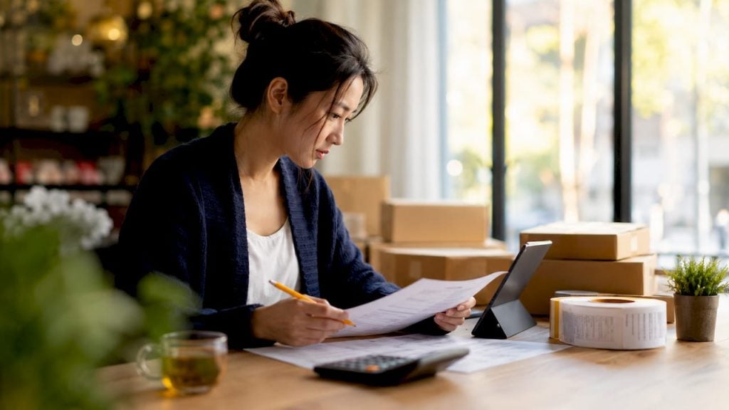 Woman analyzing eCommerce fulfillment costs at home