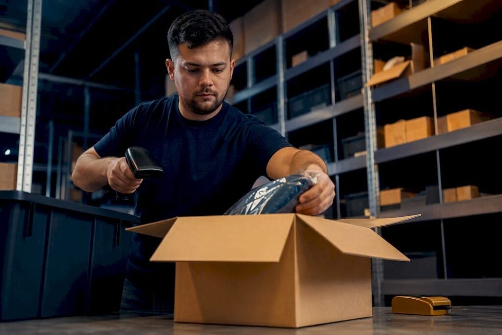 Worker transferring item into shipping carton